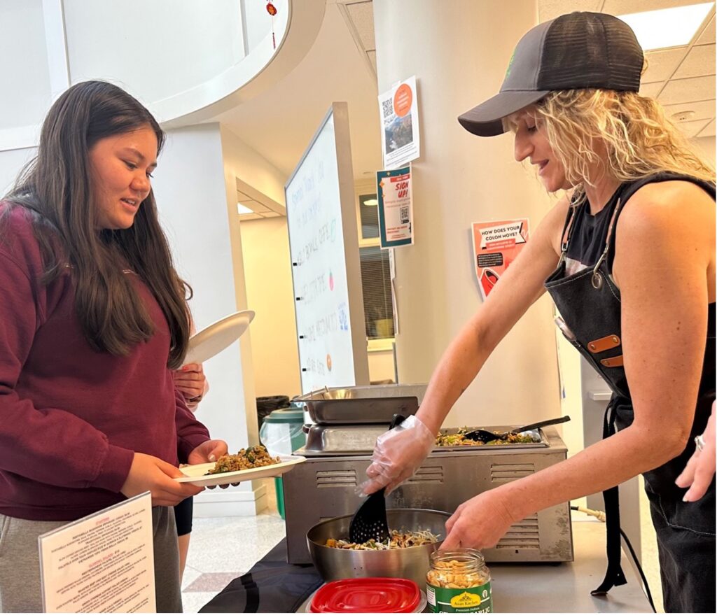 Lauren McCaughrin, owner of Globowl Cafe, prepares a serving of “The Shangri Lala” for Jasmine Gipson ’24. The red cabbage-based slaw contains local and organic ingredients.